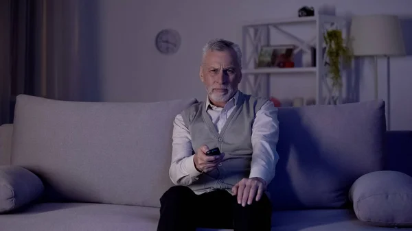 老人切换频道与遥控器 无聊和恼火的广告 — 图库照片