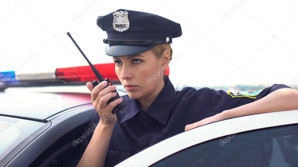 Serious police woman receiving call on radio set, emergency situation, rush