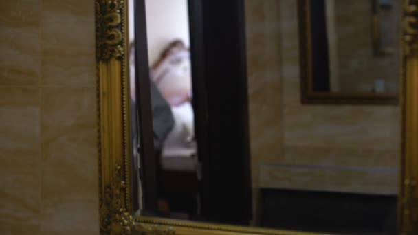 Дівчина в халаті дивиться у дзеркало після пробудження, ранковий світогляд, відображення — стокове відео