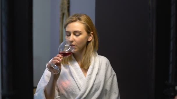 Улыбающаяся женщина пьет вино дома после тяжелого рабочего дня, отражение в зеркале — стоковое видео