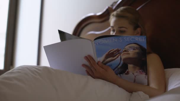 Mujer joven leyendo la revista para mujer en la cama, tiempo libre y relajación — Vídeos de Stock