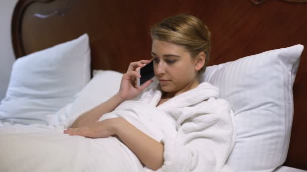 Нервова жінка лежить в ліжку, розмовляє телефоном з хлопцем, непорозуміння — стокове відео