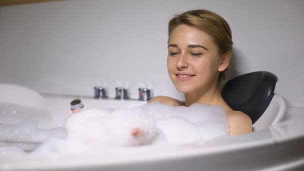 Rolig kvinnlig liggande i badet, blåsa skum bubblor i kameran, barnslig humör — Stockvideo