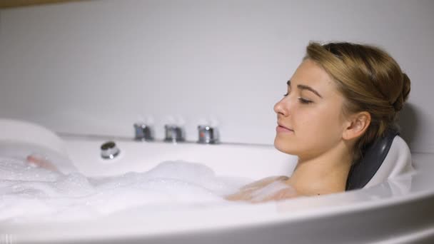 Расслабленная женщина наслаждается массажной ванной с пеной пузырьков, спа и оздоровительный — стоковое видео