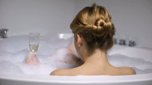Mujer bebiendo champán en el baño con burbujas de espuma, escalofriante spa, vista trasera — Vídeos de Stock