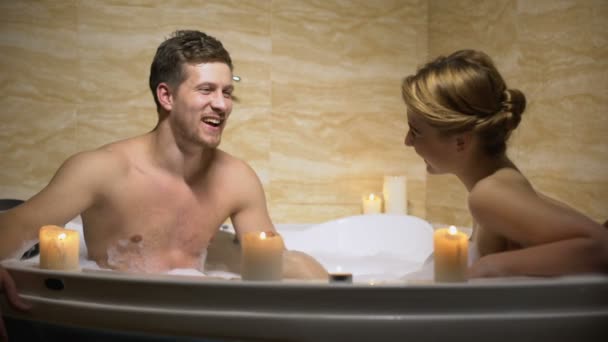 Пара флирта и смеха во время романтического вечера в ванной со свечами, любовь — стоковое видео