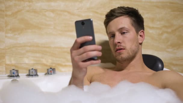 Man resting in bathtub and chatting with girlfriend, upset by canceled date — Stock Video