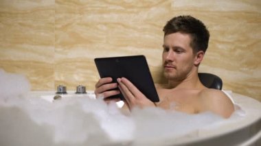 Yakışıklı adam banyo alarak ve tv programı izlerken zor iş günü sonra rahatlatıcı