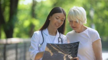 Rehabilitasyon merkezi parkta eklemlerx-ray bakarak yaşlı kadın ile Hemşire