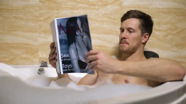Maskulin kille tar varmt avslappnande bad och läsa mens Magazine, färska nyheter — Stockvideo