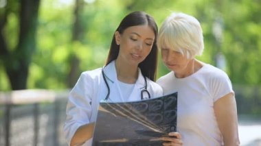 Hemşire yaşlı kadın eklem röntgen muayene sonucu gösteren, kameraya gülümseyerek