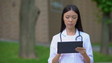 Hastane parkında tablet Pc üzerinde çalışan profesyonel kadın doktor, sağlık