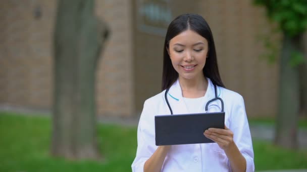 Hastane parkında tablet Pc üzerinde çalışan Gülümseyen kadın doktor, tıbbi araştırma — Stok video
