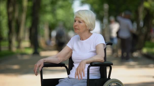 Mulher idosa perturbada sentada em cadeira de rodas no parque de repouso de idosos, doença terminal — Vídeo de Stock