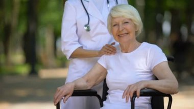 Doktor kameraya bakarak engelli yaşlı kadının omzuna el koyarak