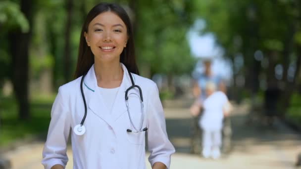 Lächelnde Ärztin blickt in Park nahe Reha-Zentrum in die Kamera — Stockvideo