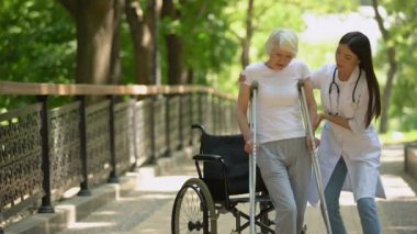Doktor koltuk değneği ile yürüyen engelli yaşlı kadın yardım, travma sonrası iyileşme