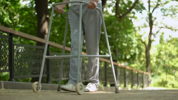 Jambes du patient se déplaçant lentement à l'aide du cadre de marche dans le parc de l'hôpital — Video