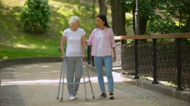 Engelli yaşlı anneannesini destekleyen kadın, hastane parkında yürüme, hastalık