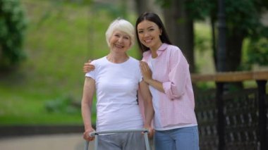 Gönüllü ve engelli yaşlı kadın hastane parkında kameraya gülümseyerek, bakım