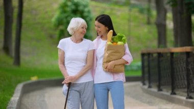 Yaşlı kadın hastaya yemek getiren torunu, hastane parkında yürüyor
