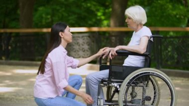 Gönüllü tekerlekli sandalyede ağlayan kadın ile konuşuyor, psikolojik destek, park