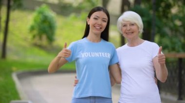 Kadın gönüllü ve yaşlı kadın başparmak gösteren, sosyal destek projesi