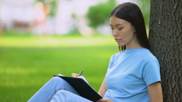 Mujer estudiante escribiendo ensayo sentado parque, periodista artículo de trabajo, notas — Vídeo de stock