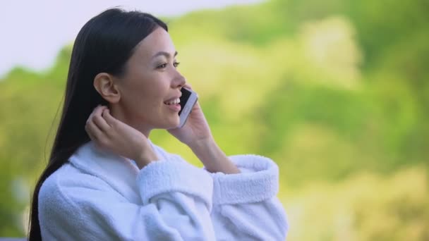 Joyeux attrayant femelle en peignoir parlant au téléphone, vacances station de luxe — Video