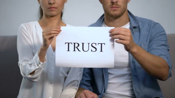 Serious couple holding cardboard with trust word, family relationship, attitude — Stock Video