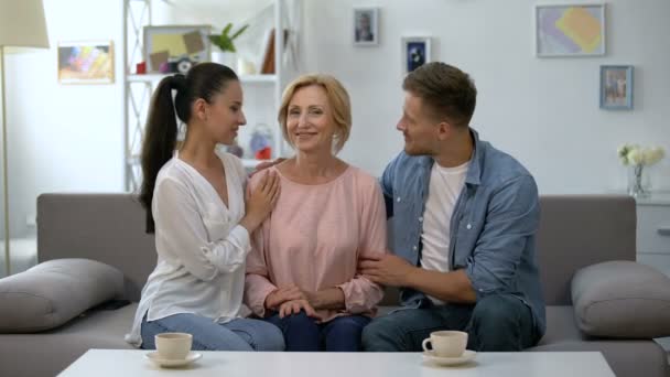 Casal jovem e sogra de mãos dadas, sorrindo para a câmera, felizes juntos — Vídeo de Stock