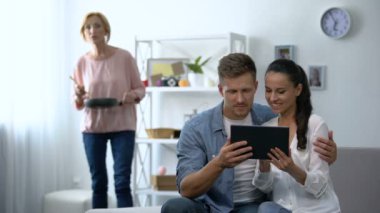 Meraklı kayınvalide görünümlü genç çift evde tablet Pc üzerinde kaydırma