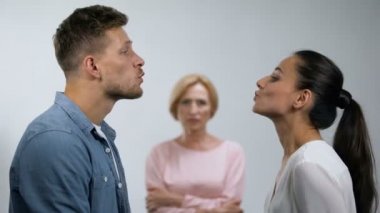 Elleri ile hoşnutsuz anne hava öpücük göndererek genç çift bakarak geçti