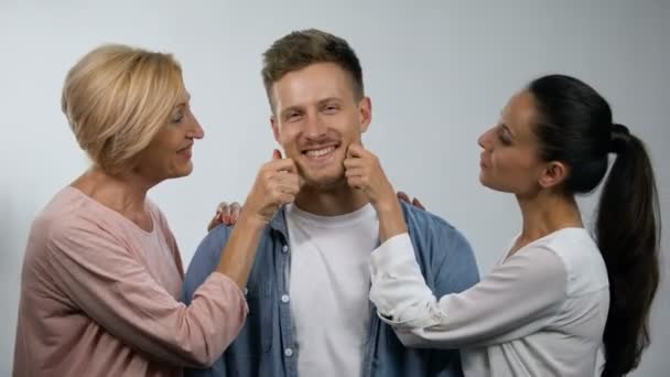 Frau und Mutter kneifen jungen Mann in die Wangen, Überbehütung in der Familie — Stockvideo