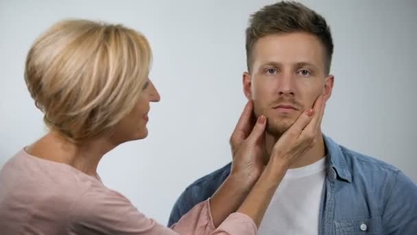 Mère souriante pincant les joues irritées de son fils, garde d'enfants adultes, surprotection — Video