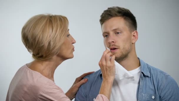 Madre allegra che asciuga la bocca al figlio adulto irritato, effetto iperprotettivo — Video Stock