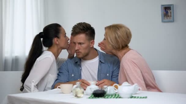 Hombre escuchando esposa y suegra susurrando al oído, eligiendo el consejo de mamá — Vídeos de Stock