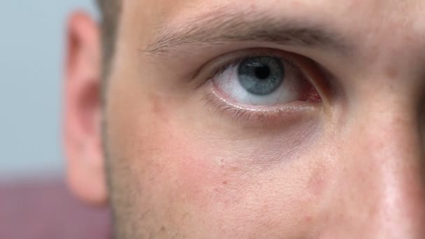 Genç adam kameraya bakıyor, göz yorgunluğu ve kırmızı gözlerden muzdarip, yorgunluk — Stok video