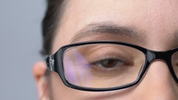Женщина в очках моргает, устала от плохого зрения, проблем со зрением, крупным планом — стоковое видео