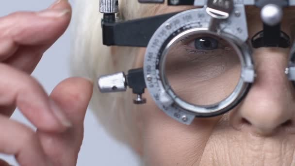 Female pensioner checking vision through phoropter, ophthalmology examination — Stock Video