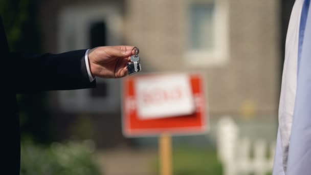Agente de alquiler dando llaves de apartamento a nuevo propietario contra letrero vendido — Vídeos de Stock