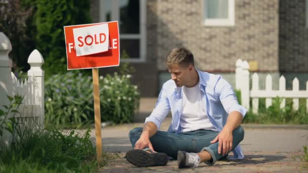 Mannelijke huilen zittend op de grond in de buurt van verkochte bord, staat neemt eigendom voor schuld — Stockvideo