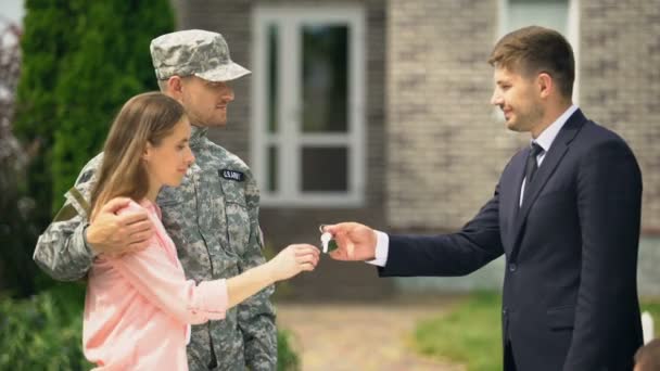 Представитель государства в костюме вручает ключи от дома ветерану войны и его жене — стоковое видео