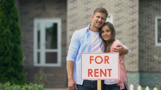 Happy couple hugging near for rent signboard, family renting out summer house — Stock Video