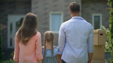 Mutlu aile kucaklayan, yeni evde hareketli, uzun zamandır beklenen satın alma, geri görünümü