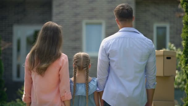 Família feliz abraçando, movendo-se em nova casa, compra tão esperada, visão traseira — Vídeo de Stock