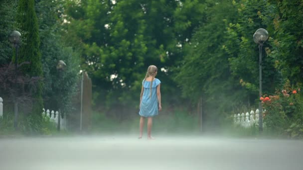 Веселая девушка машет рукой, стоя босиком в тумане, таинственная атмосфера — стоковое видео
