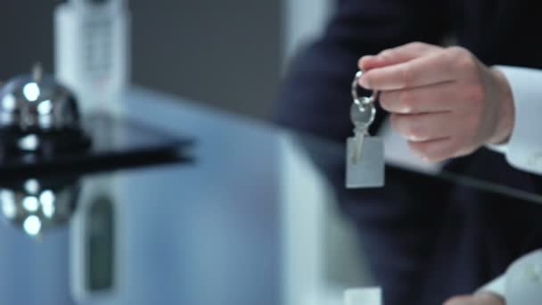 Manlig receptionist hand ger kvinnliga besökare nyckel på kedjan, servicekvalitet, resa — Stockvideo