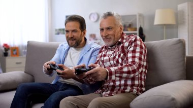 Yetişkin baba ve oğlu birlikte eğlenmek video oyunu oynarken, boş zaman aktivitesi