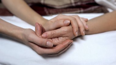 Sıcak kızlar elleri tutarak ve yatakta hasta anne sakinleştirici, yardım